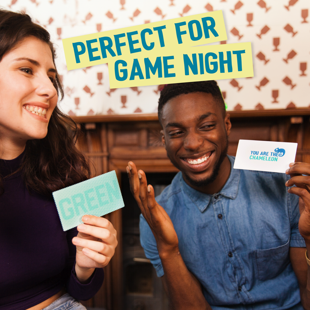 Two friends playing the Chameleon travel game holding up game cards one showing GREEN text and the other YOU ARE THE CHAMELEON