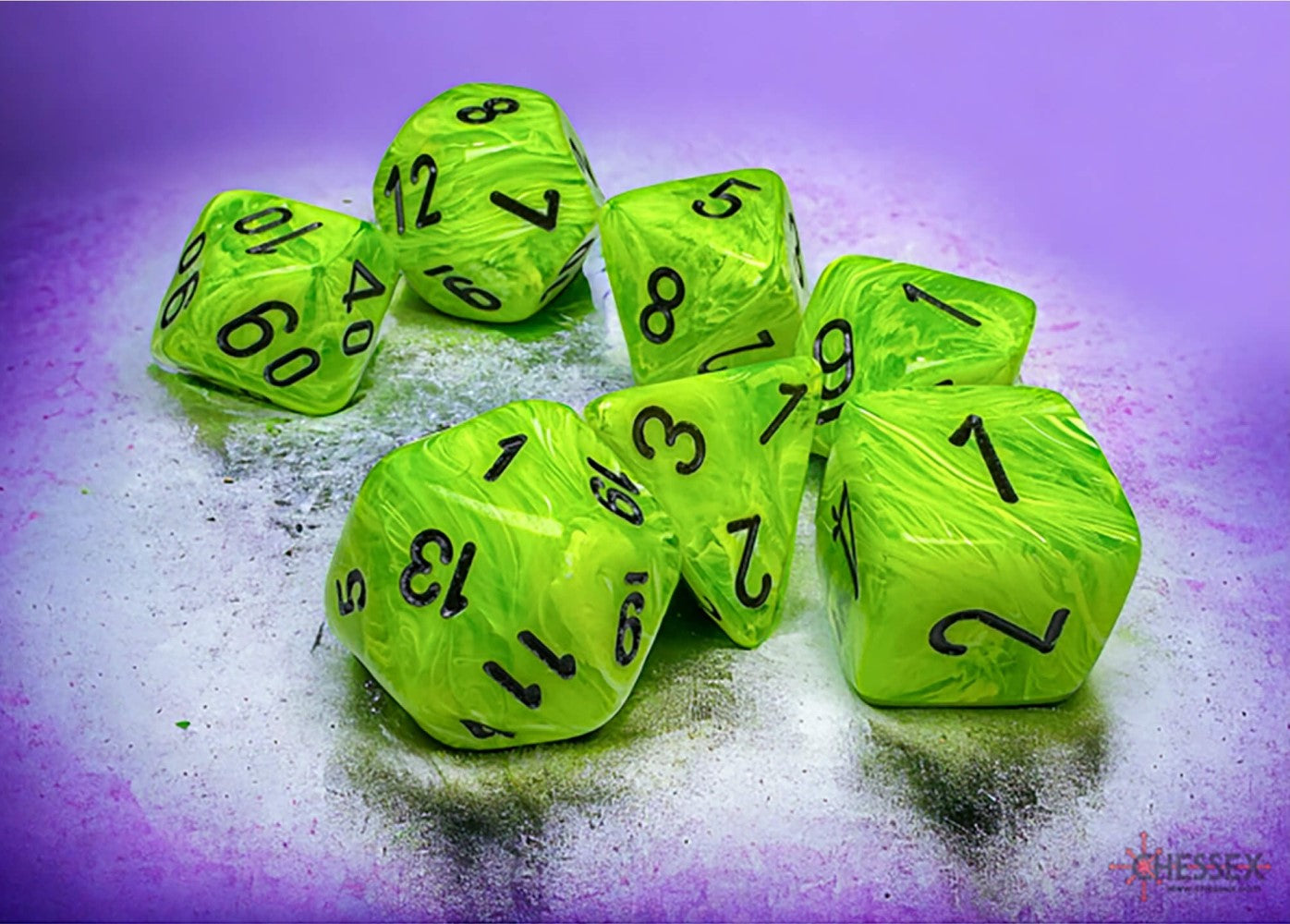 Scattered group of green marbled polyhedral dice with black numbers on a textured purple surface