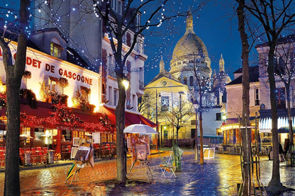Illuminated Montmartre square at night with wet cobblestones reflecting lights from cafes and artist easels, Sacré-Cœur in background