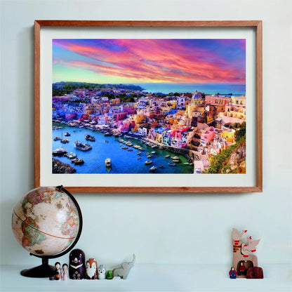 Framed puzzle of a vibrant, colorful coastal town with boats in its bay, under a stunning pink and purple sunset