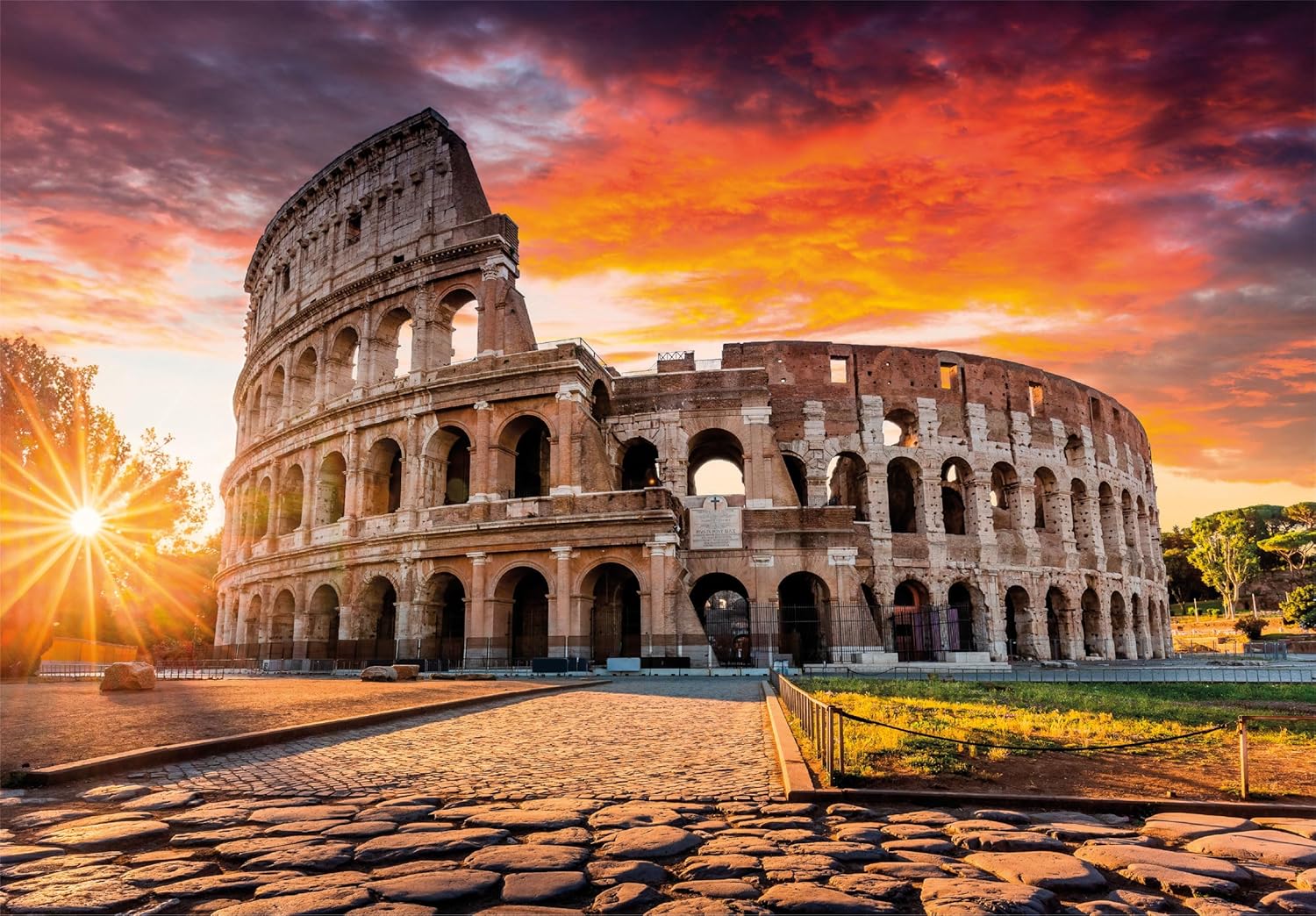 The Colosseum at sunset with a sunburst and a dramatic orange-red sky