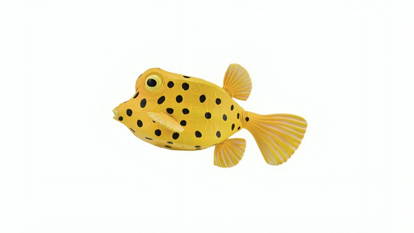 A yellow boxfish figurine with black spots against a white background