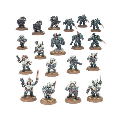 Twenty-plus miniature futuristic soldiers standing in various poses, some in dark green armor, others in cream, holding weapons