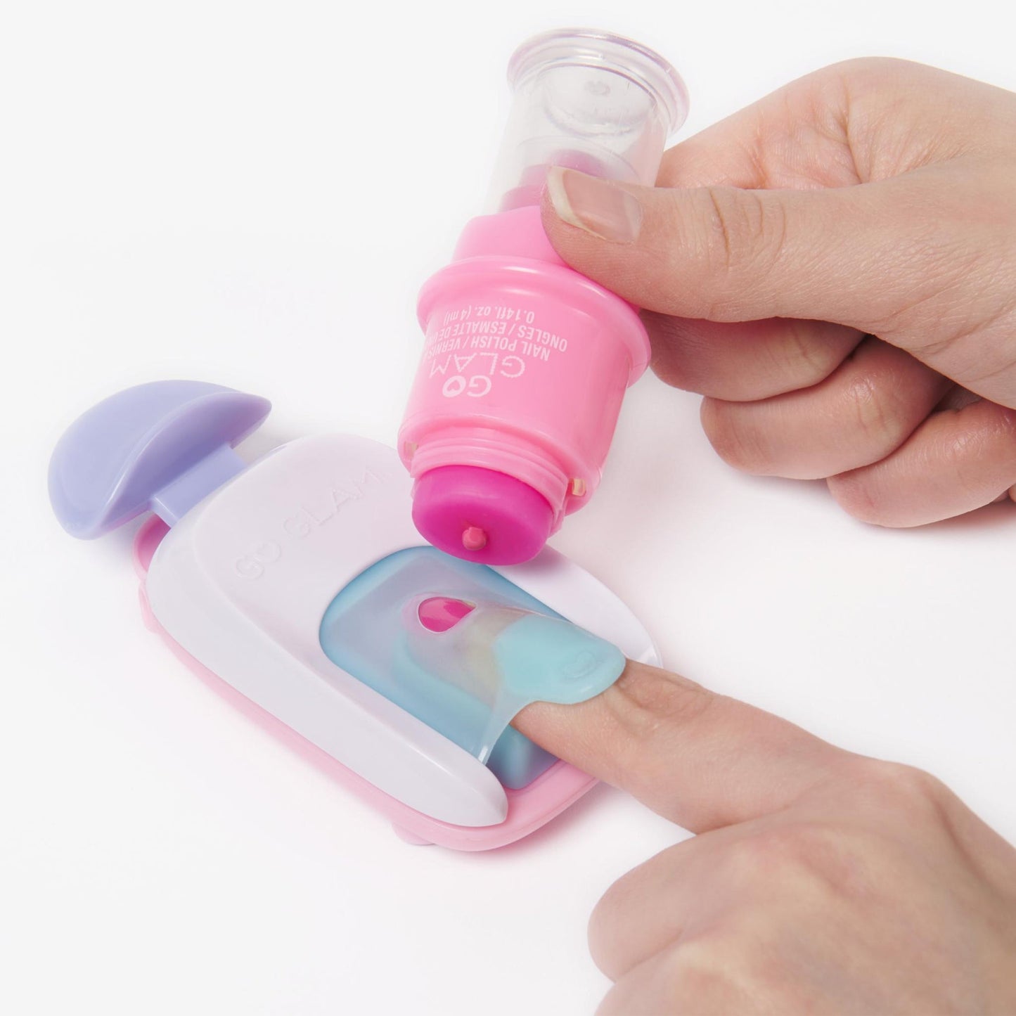 Hand holds pink Go Glam nail polish bottle dropping polish onto a pink and white nail stamper, a finger is inside the stamper, ready for nail art