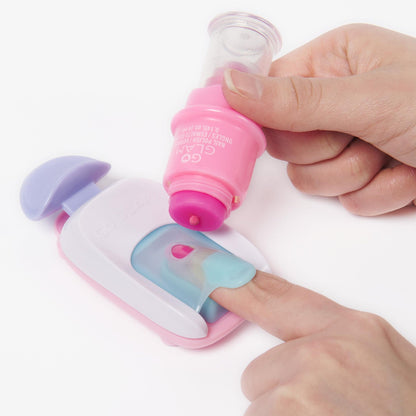 Hand holds pink Go Glam nail polish bottle dropping polish onto a pink and white nail stamper, a finger is inside the stamper, ready for nail art