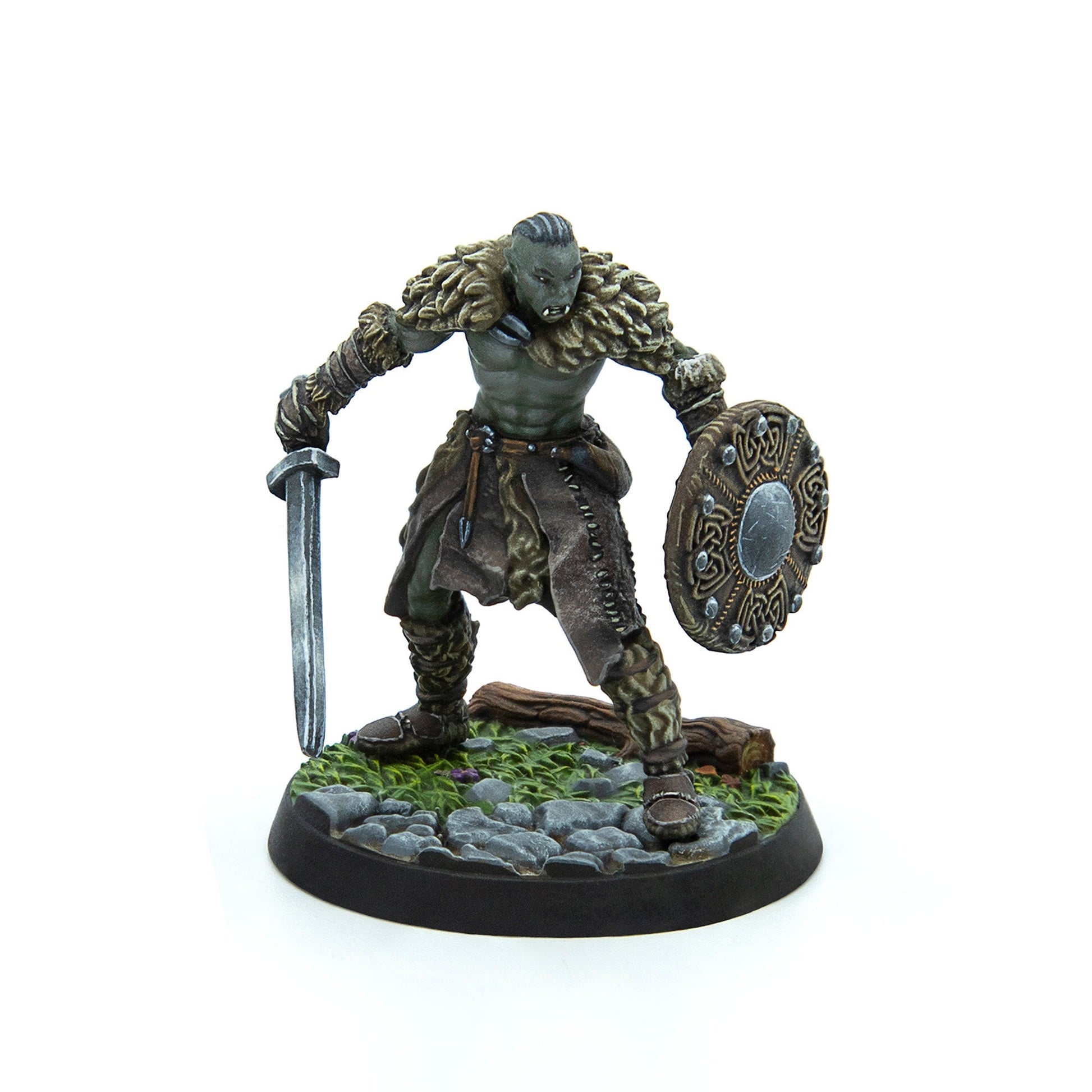 Green-skinned orc miniature with tusks, wearing fur armor, holding a sword and ornate round shield, standing on a rocky base