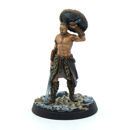 Painted miniature of a muscular, shirtless warrior holding a round shield overhead and a long sword