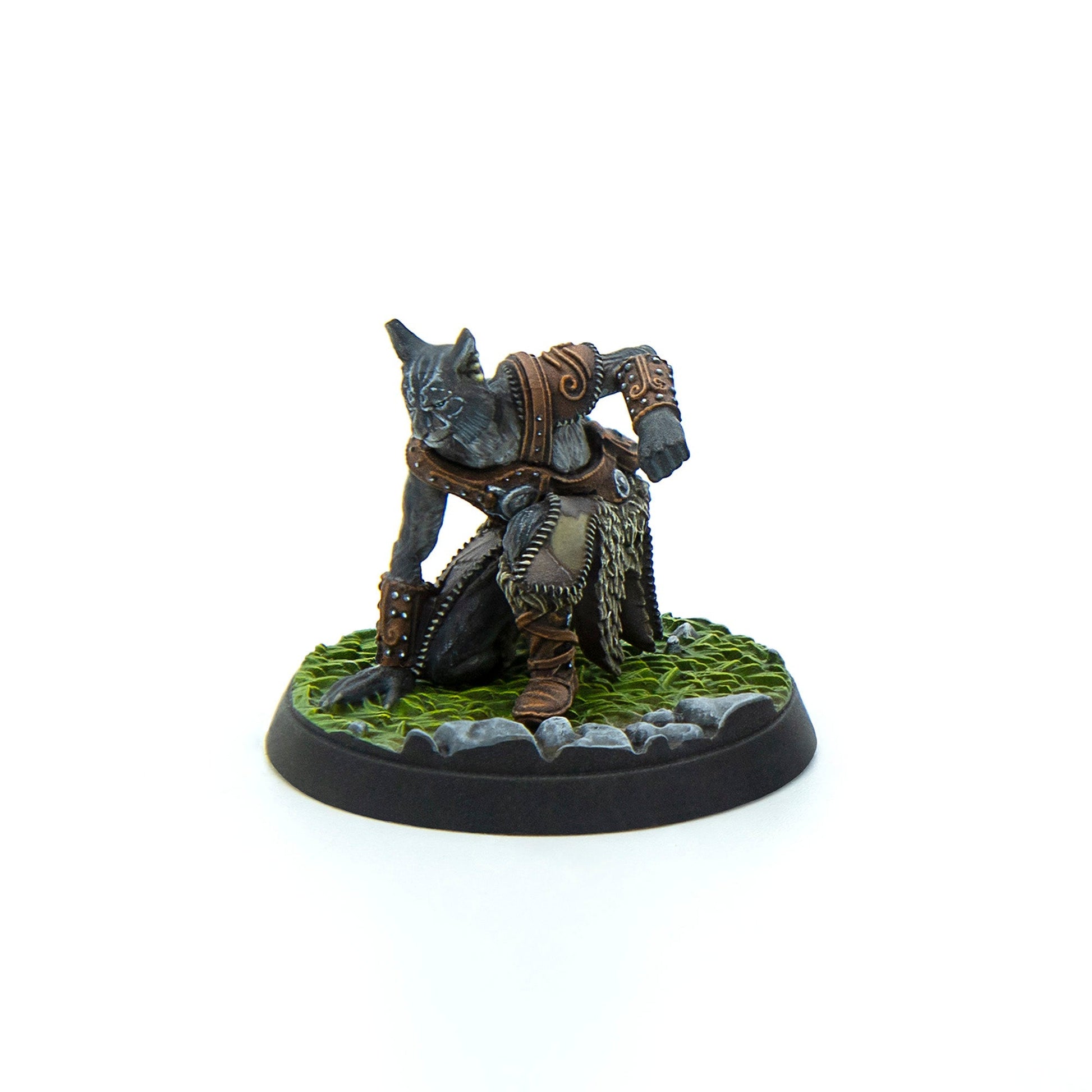 A detailed cat warrior miniature in brown leather and fur armor, crouched and poised on a grassy base with rocks
