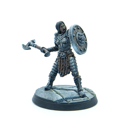 Dark-skinned female warrior miniature in ornate armor, wielding an axe and spiked shield, roaring