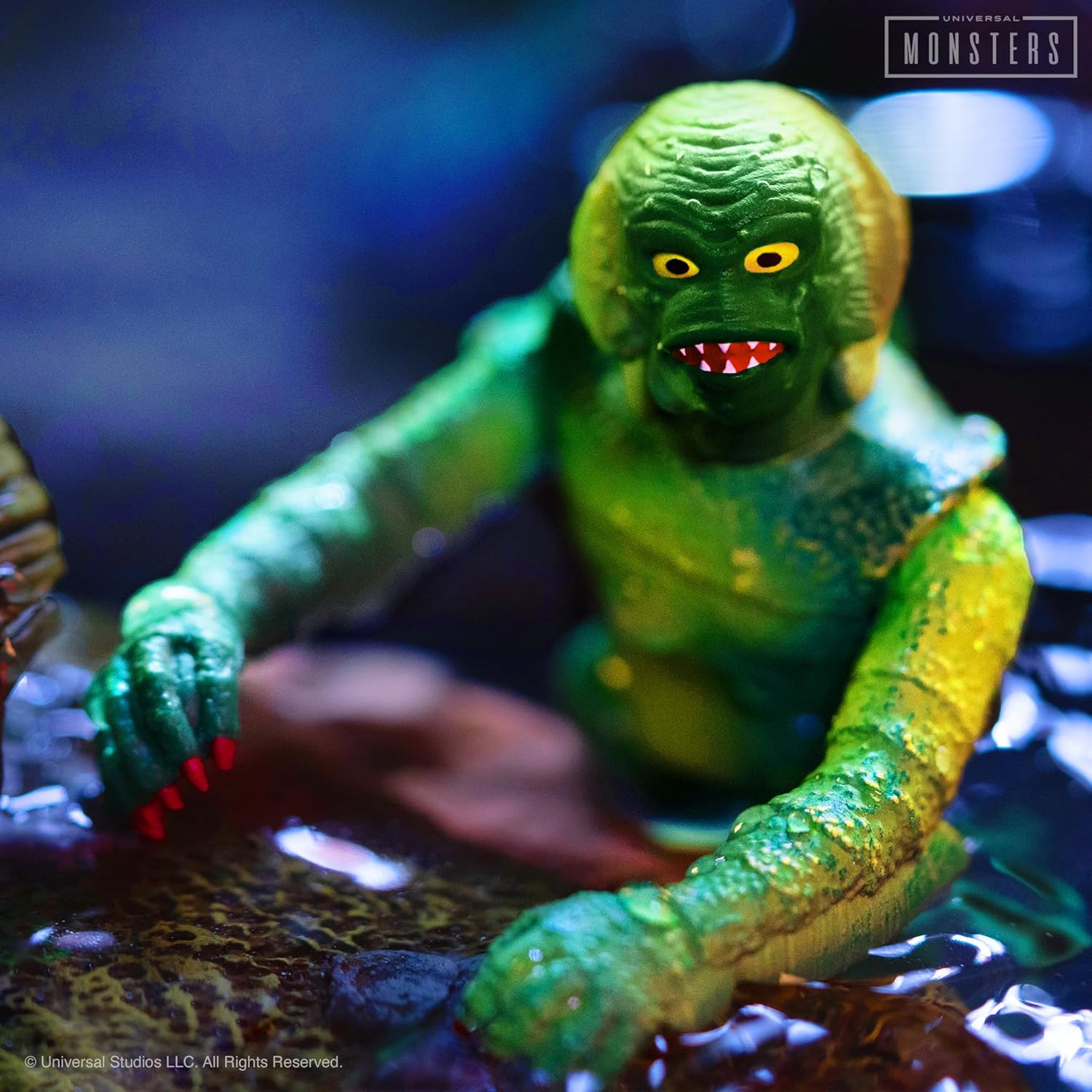 Green Creature from the Black Lagoon figure with striking yellow eyes and red teeth, emerging from dark, murky water