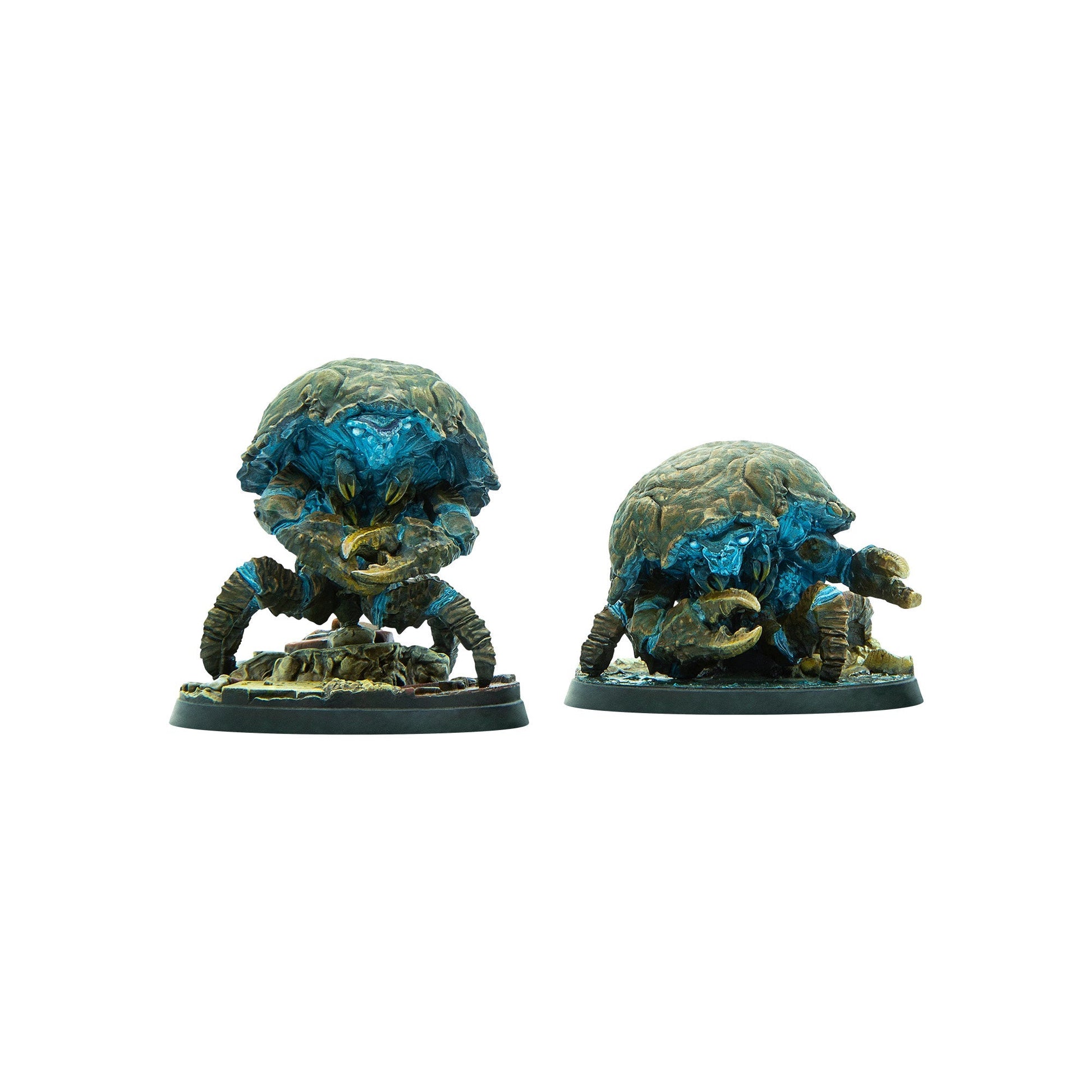 Two armored crab-like miniatures with glowing blue faces and large claws stand on rocky bases