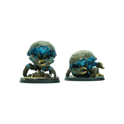 Two armored crab-like miniatures with glowing blue faces and large claws stand on rocky bases