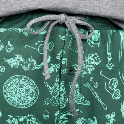 Close-up of a green garment with teal fantasy-themed illustrations, a grey drawstring bow, and a button