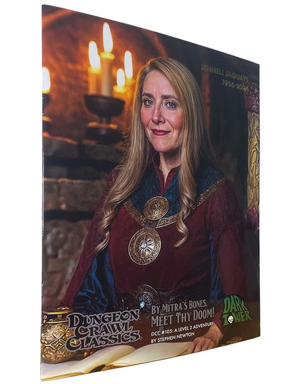 A smiling Jenell Jaquays (1956-2023) in fantasy robes on a Dungeon Crawl Classics adventure cover with a candlelit background