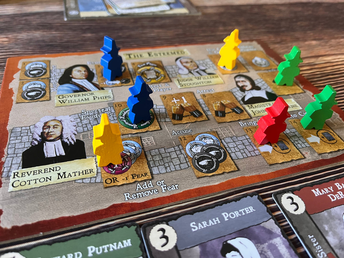 A close-up of a board game with blue, yellow, red, and green pawns on action spaces like &#39;Accuse&#39; and &#39;Spectral Evidence&#39;