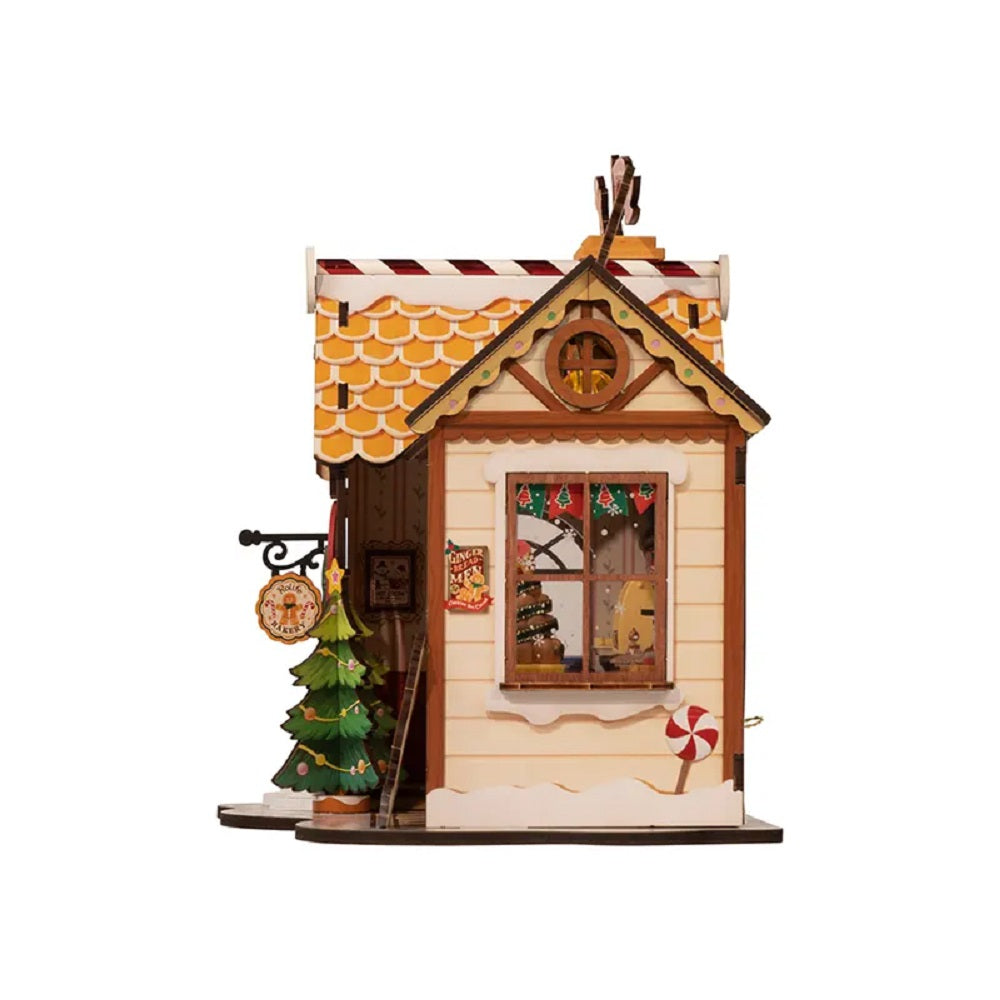 Miniature wooden Christmas house or gingerbread bakery model with snow, a candy cane, and a Christmas tree
