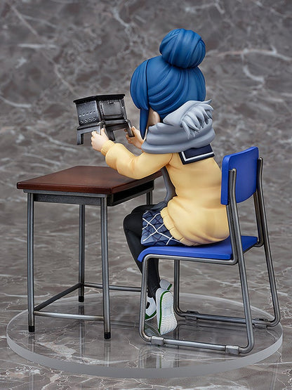 Anime figure of a girl with blue hair in a yellow jacket sitting at a desk holding a mini stove