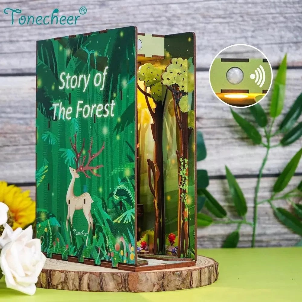 An open wooden book titled "Story of The Forest" displays an illuminated forest diorama with a deer. Sensor detail
