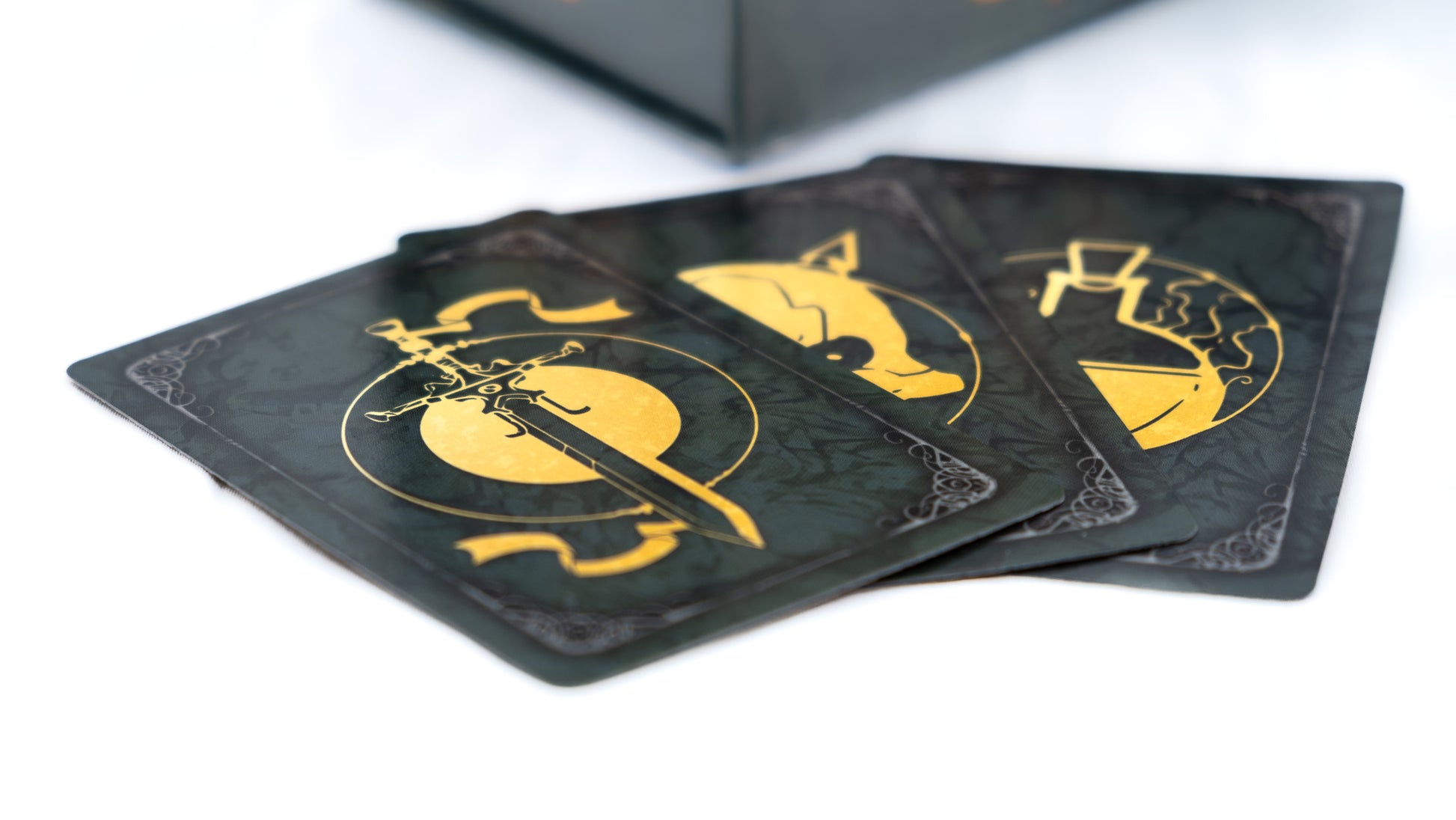 Close-up of three black fantasy game cards displaying golden symbols: sword, fox, and beaker