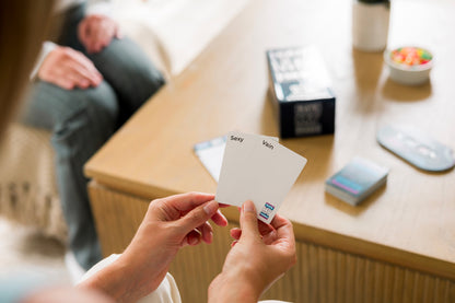 Hands holding Rate My Friends cards that say Sexy and Vain during a game