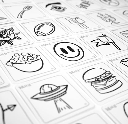 White game cards with black line drawings like a smiley face, burger, and UFO, arranged in a grid