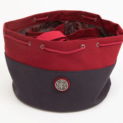 A two-tone red and navy Critical Role Bailey's drawstring bag, open to reveal internal compartments and a logo badge