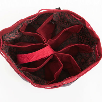 Open red drawstring dice bag with eight interior compartments and a dark patterned lining