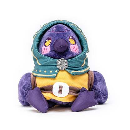 A purple bird plush in a teal hooded cloak with yellow trim and a Critical Role pin, sitting