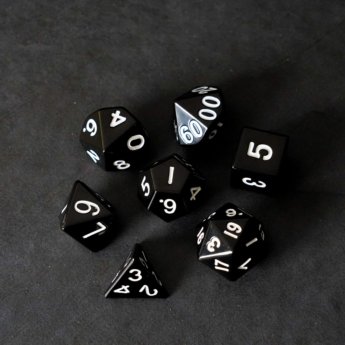 Full black metal polyhedral dice set fanned out on dark background premium RPG tabletop gaming dice