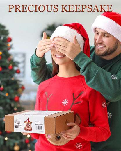 Man surprises woman with a "Classic Carousel Kit" gift while covering her eyes. Both wear Santa hats