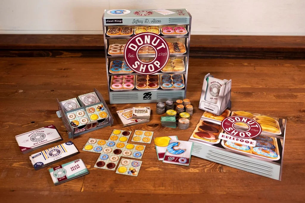 25th Century Games Donut Shop board game set featuring a display case rulebook game pieces tokens and cards arranged on a wooden table