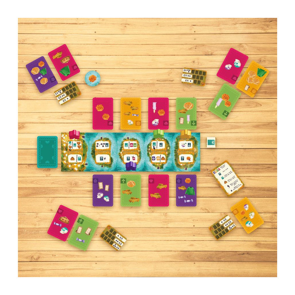 Colourful board game components, including various cards and tokens, arranged on a light wooden tabletop