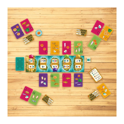 Colourful board game components, including various cards and tokens, arranged on a light wooden tabletop