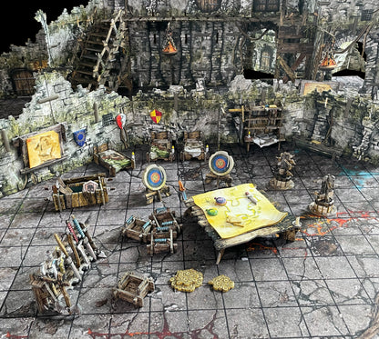 A miniature tabletop RPG dungeon setup with stone walls, stairs, beds, a map, weapon racks, and gold coins on a grid mat.