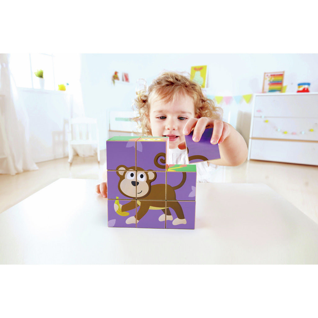 Curly-haired child places a cube, completing a purple monkey puzzle holding a banana.
