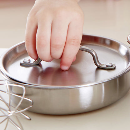 Child's hand holding a miniature stainless steel play kitchen pot lid