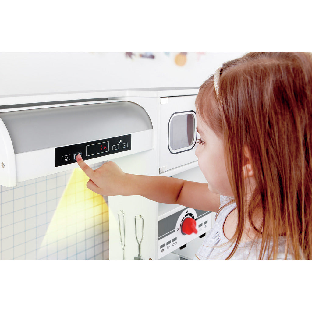 Child pushing a button on a play kitchen range hood with a bright yellow light shining down