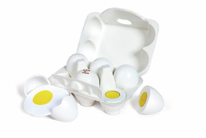 Six white play eggs in a carton; some are split open to show hard-boiled yellow yolks