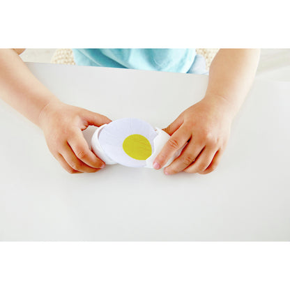 Child’s hands holding a cracked toy egg, revealing a felt egg slice with yellow yolk
