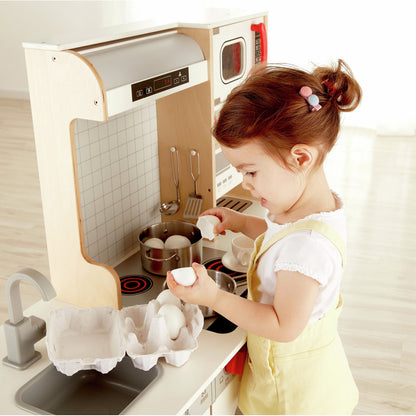 Toddler playing with a wooden kitchen set, cracking toy eggs into a pot