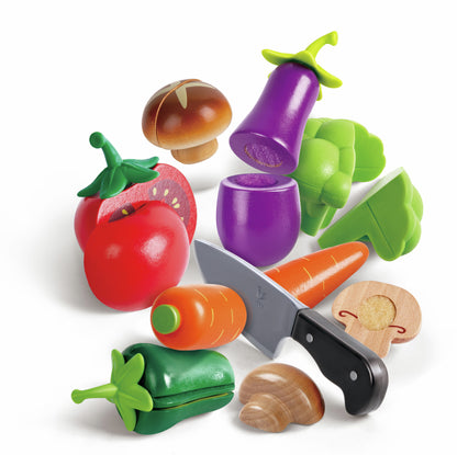 Colorful wooden and plastic play vegetables and a toy knife, including cut tomato, carrot, and mushroom pieces