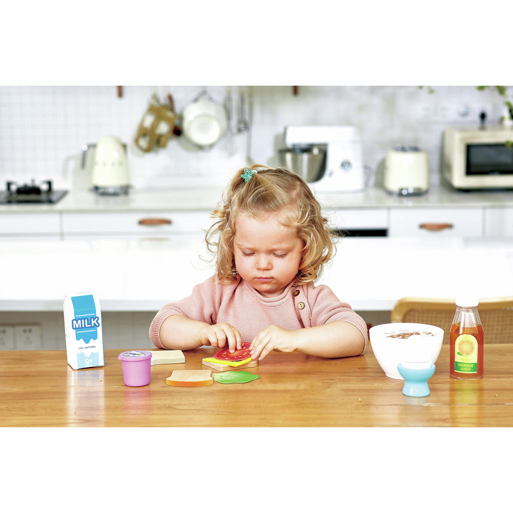 Young child focused on assembling a toy wooden sandwich in a kitchen setting