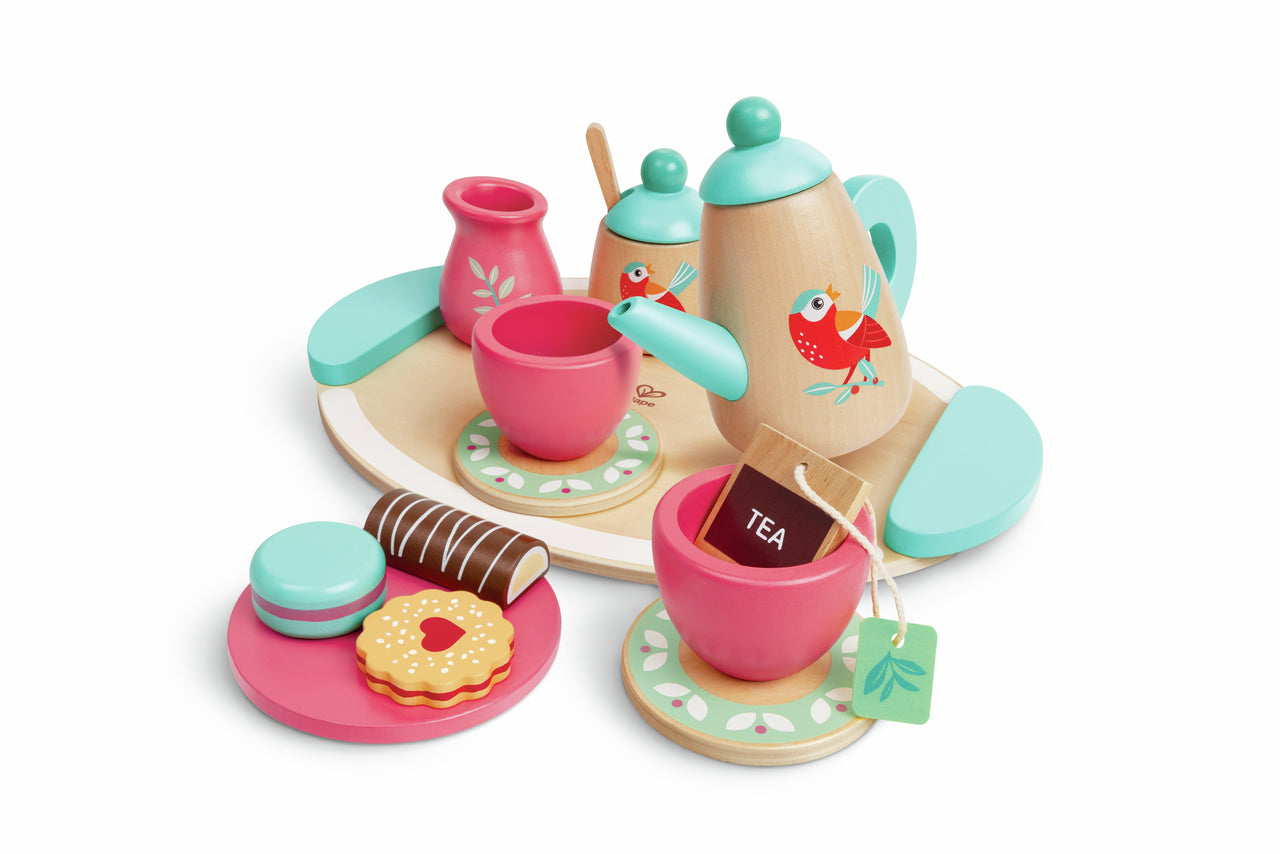 Pink and mint wooden toy tea set with bird-decorated teapot, cups, saucers, and cookies on a serving tray