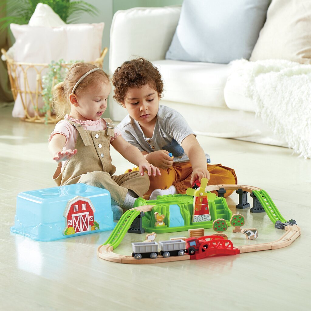 Two young children playing with a wooden farm train set and tracks on the floor