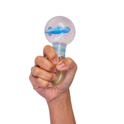 Hand gripping a glitter stress toy with a clear globe top containing a blue plane figure