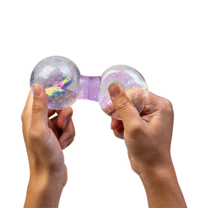 Hands squeezing a clear, glitter-filled stress toy with a unicorn figure