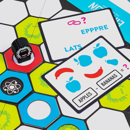 Close-up of a board game showing a black playing piece on a hexagon board and two riddle cards, one with apples and bananas