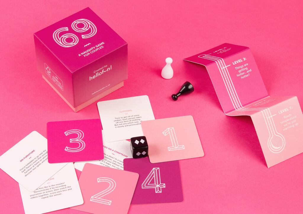 69 A Naughty Game for Couples featuring a pink game box game board number cards white and black pawns and a black dice all on a hot pink background