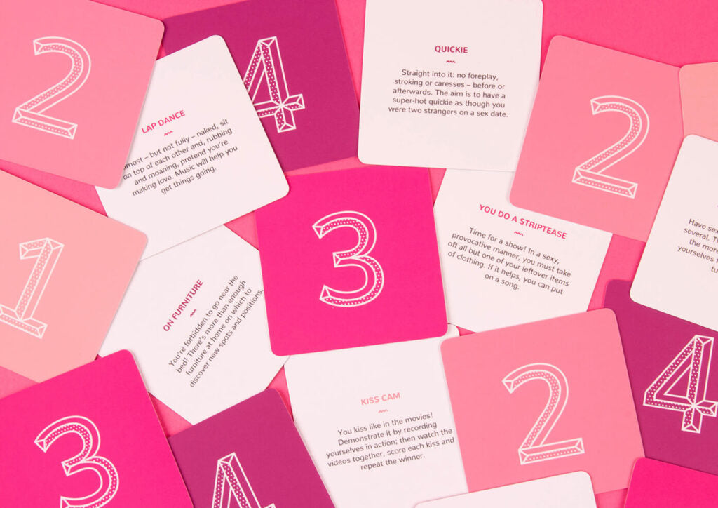 Pink and magenta cards from 69 A Naughty Game for Couples showing dares like Lap Dance Quickie on Furniture You Do a Striptease and Kiss Cam