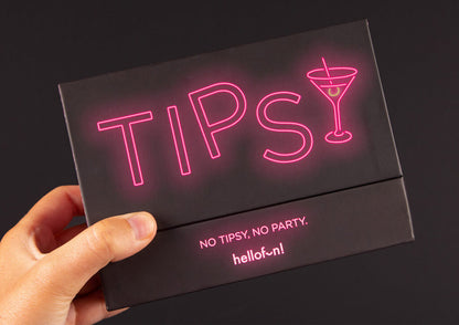 Black game box held by a hand. "TIPSY" in pink neon, with a martini glass and "NO TIPSY, NO PARTY." below
